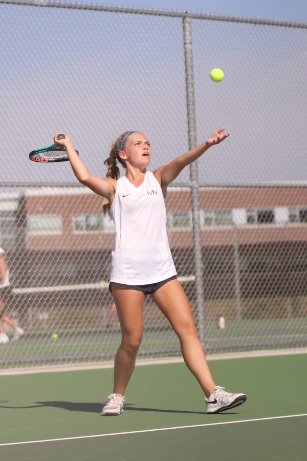 Tossing the ball into the air, junior Bri Coup serves to her opponent.