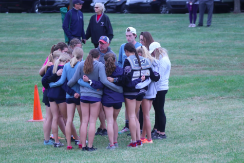 Before the girls varsity race, the team huddles with the coaches to share some last. minute words of wisdom.