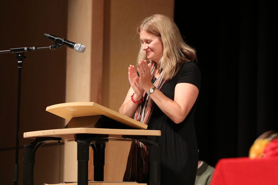 Smiling, Spanish teacher Jan Good-Bollinger announces a round of applause for the new inductees.