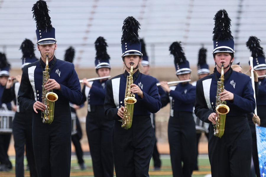 Alongside seniors Ben Baumgart and Julianne Long, sophomore Kate Marten (center) plays her saxophone with the marching band at the Emporia State Marching Festival Wednesday, Oct. 6.