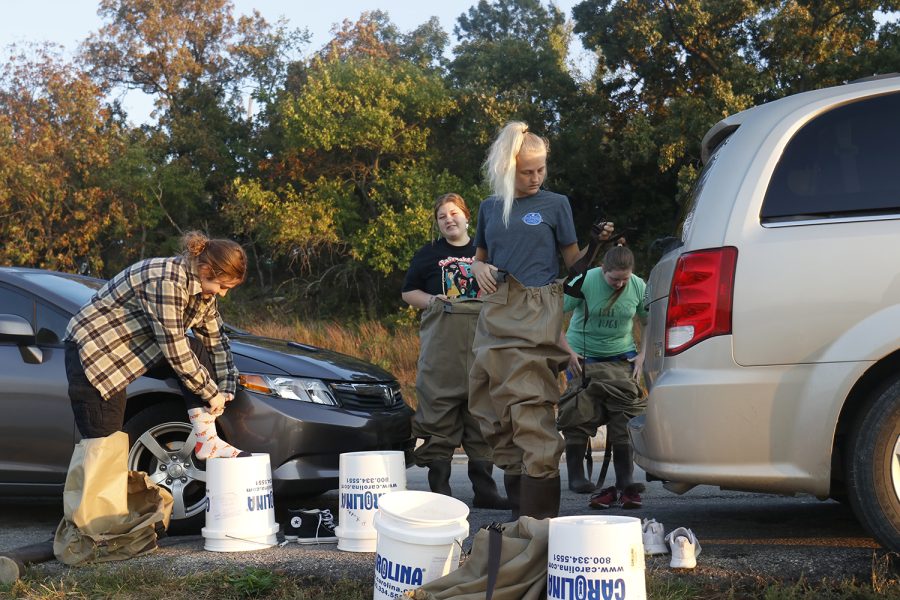 On the side of the road, Environmental Resources and Wildlife Science students put on waders before going into the water to collect plants.