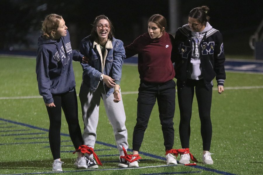 Laughing as they finish tying off the bandanas, seniors Damara Stevens, Maddy Williams, Anna Brazil and Quincy Hubert get ready for a five legged-race.