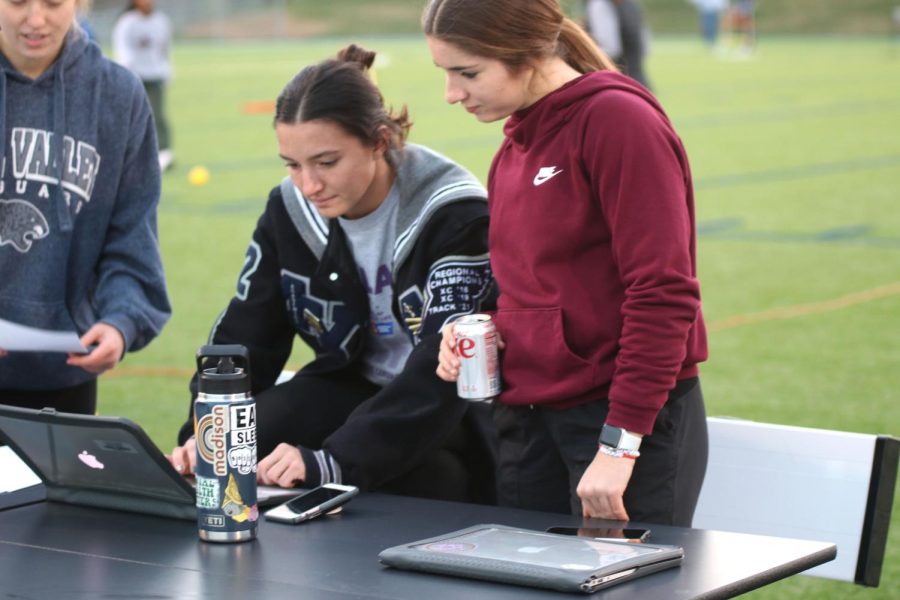 Looking down at the screen, seniors Anna Brazil and Quincy Hubert check participants in. 