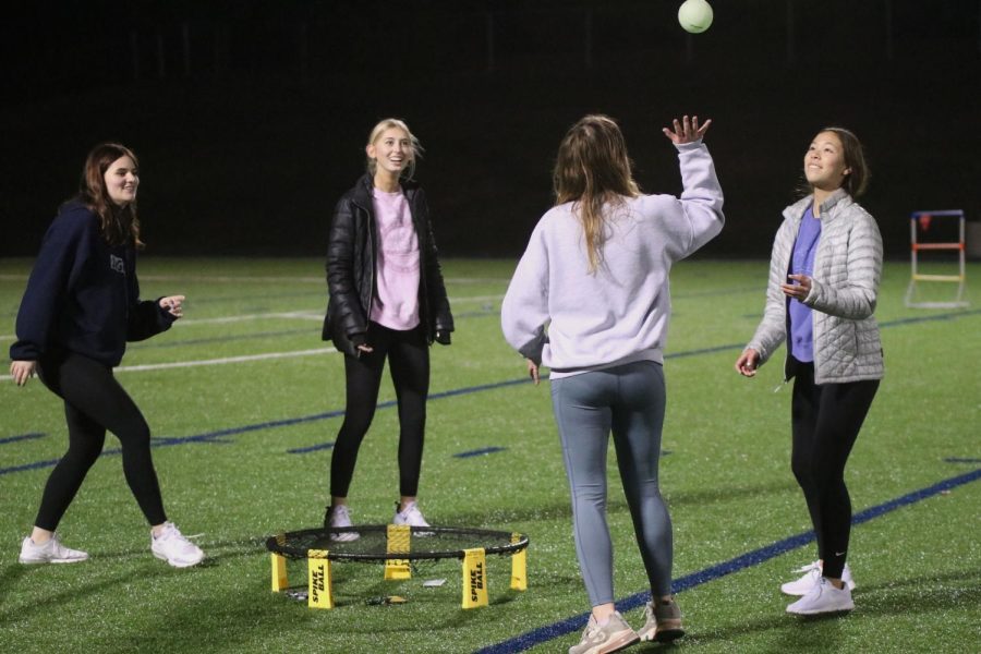 Standing around the net, sophomores Banner Hall and Natalie Moreland along with junior Kateyn Krosky play spikeball after getting out in the cornhole tournament. 