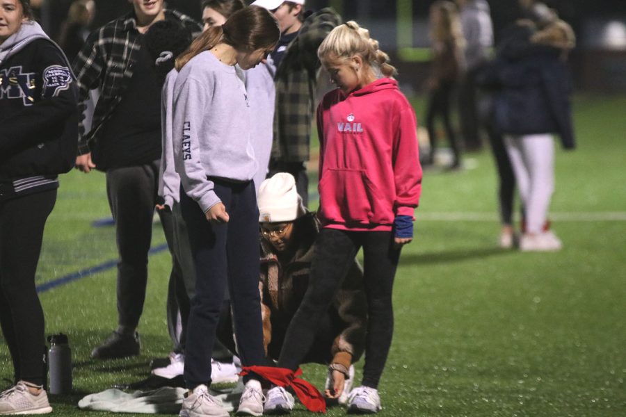 Tying the bandana around their ankles, senior Olivia Franco helps juniors Sidney Claeys and Brianna Coup get ready for the three-legged-race. 