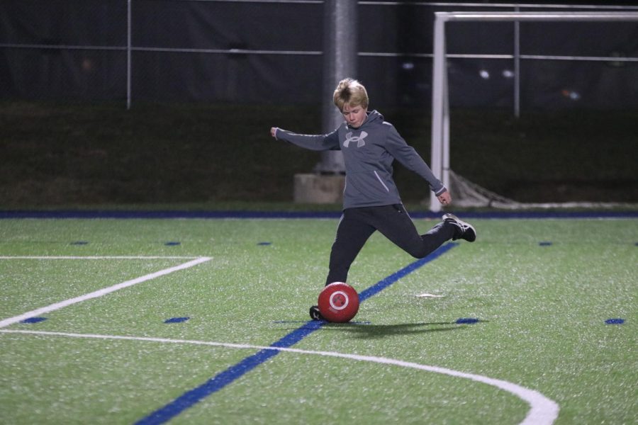 In between events, middle schooler Ben Muller kicks the ball into the soccer goal while he waits. 