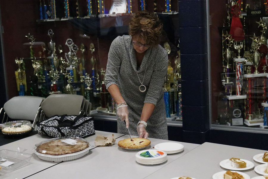 As she helps set up the feast, business teacher Dianna Heffernon-Meyers cuts the pie for the dessert table. 
