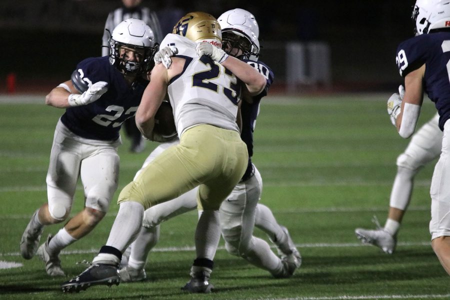 Tackling his opponent, junior defensive back Mikey Bergeron pushes him back to prevent him from advancing further down the field.