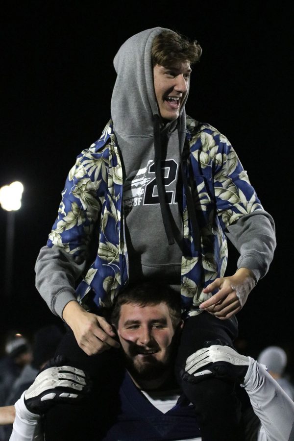 Up on senior defensive lineman Cole Seyb’s shoulders, senior Garrett Cumbie looks to senior Henry Coulson before taking a picture together.