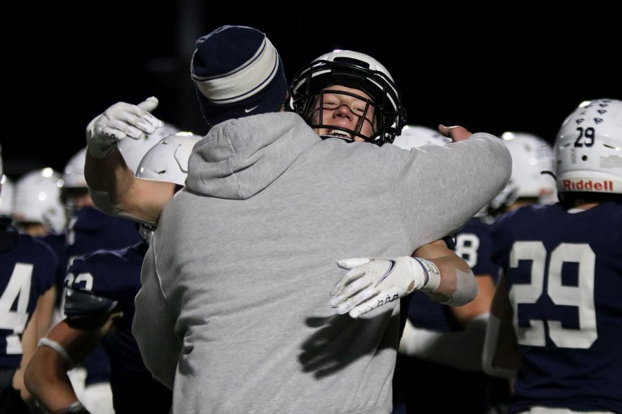 Assistant coach Drew Hudgins hugs junior defensive back Mikey Bergeron to congratulate him on the substate championship and advancing to state.