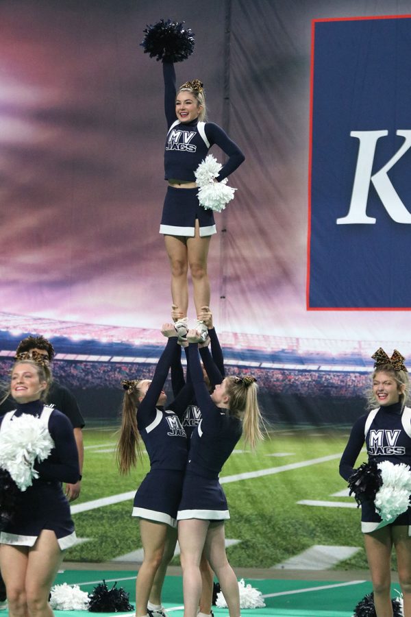 Stunted up into the air, sophomore Madeline Epperson smiles to the crowd during her performance of the fight song.