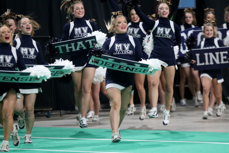 With a sign in hand, freshman Madeline Dibble pumps up the crowd before starting her routine.