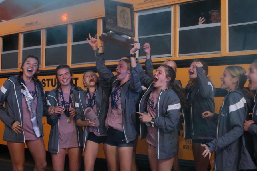After exiting the bus, the girls cross country team jumps together in celebration of their win. 
