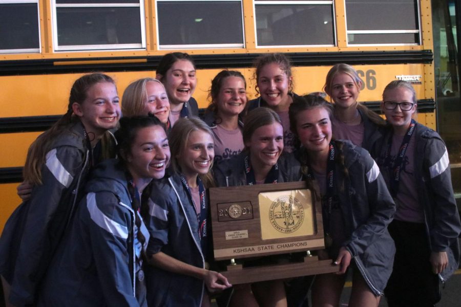 Trophy in hand, the girls cross country team poses together for a team photo. The girls took home their third state title in four years with sophomore A.J. Vega and senior Chase Schieber also medaled at the state meet in Wichita Saturday, Oct. 30. 