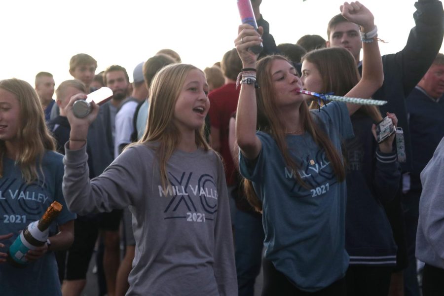 Confetti cannons in hand, freshmen Maggie Wieland and Seville Skinner wait for the bus of cross country members to arrive. 