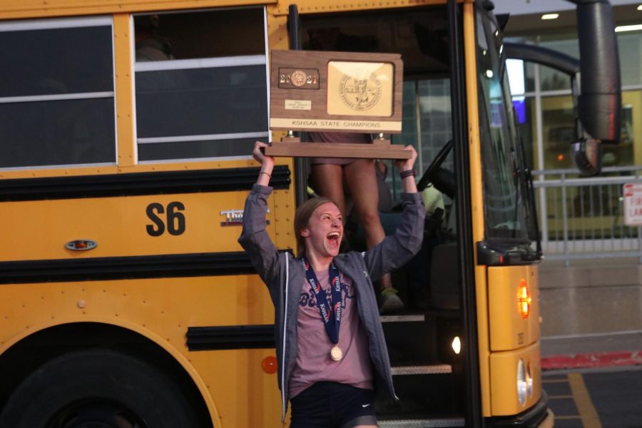 Exiting the bus, senior Katie Schwartzkopf raises the trophy above her head in celebration. 