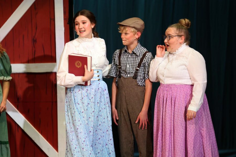 Book in hand, junior Asa Esparza stands beside middle schooler Kai Campbell and senior Hayley O’Keefe. 