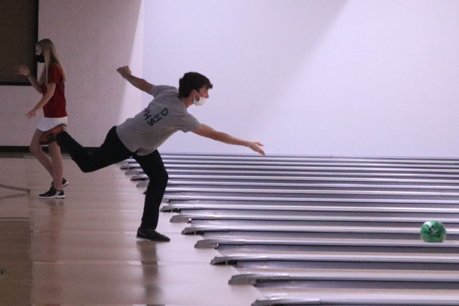 Standing on one foot, senior Jack Weber extends his arms towards the pins. 