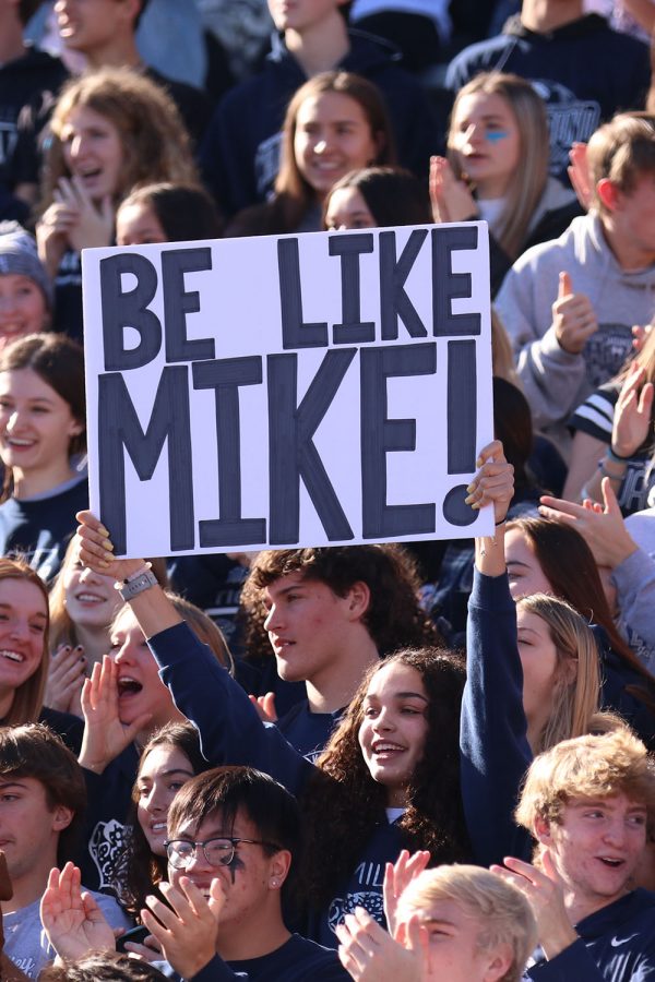 With sign in hand, junior Olivia Page cheers on the team as they are running out onto the field. 