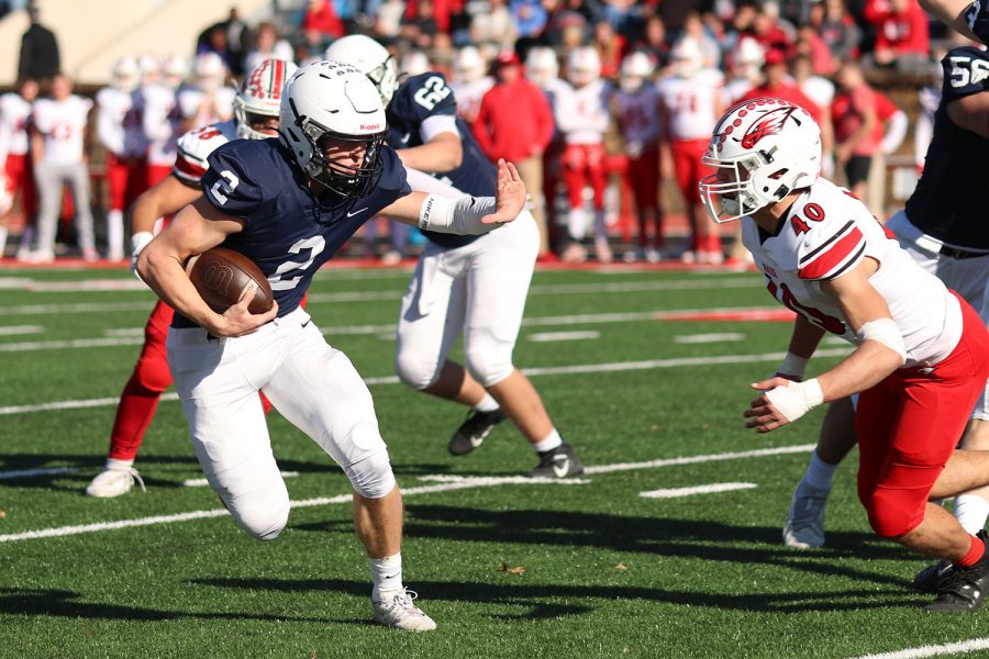 While running the ball, junior quarterback Hayden Jay puts his hand out to prepare to stop the opposing player. 