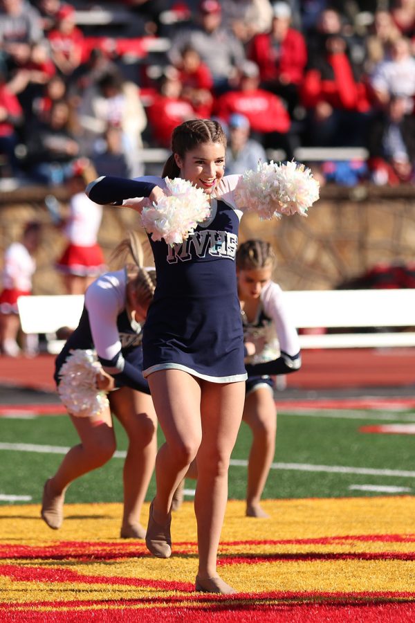 During the halftime performance, senior Anna Brazil shakes her pom-poms facing the crowd. 