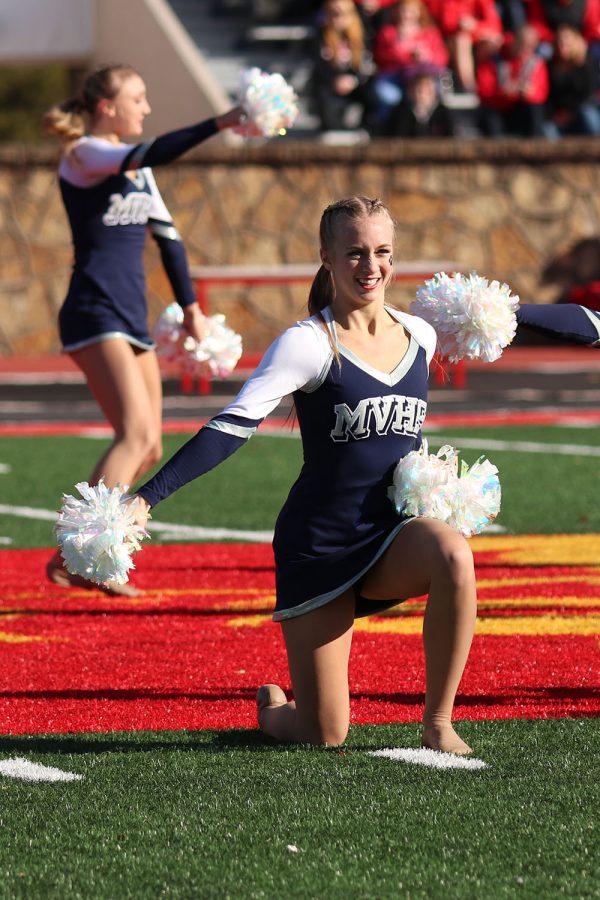 Kneeling down, senior Hadley Skinner smiles at the crowd during the Silver Stars performance.