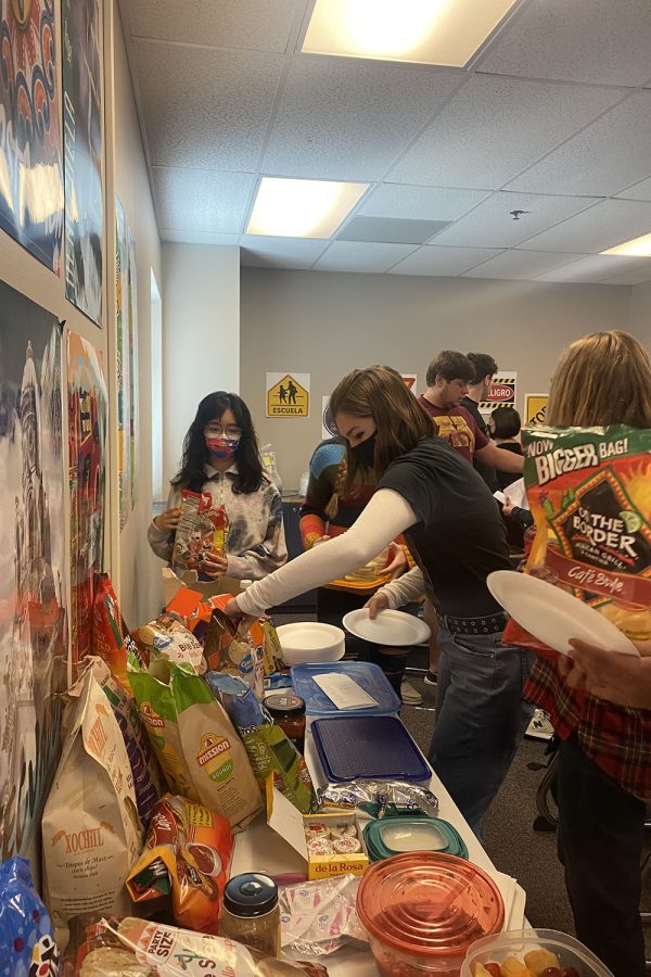 Reaching for a bag of tortilla chips, senior Grace Emerson participates in the Spanish Día de los Muertos (Day of the Dead) celebration in her Spanish V class 