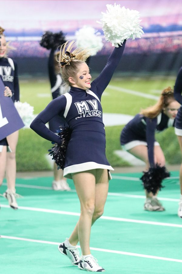 Before the performance begins, sophomore Claire Moberly helps fire up the crowd by shaking her poms and smiling. 