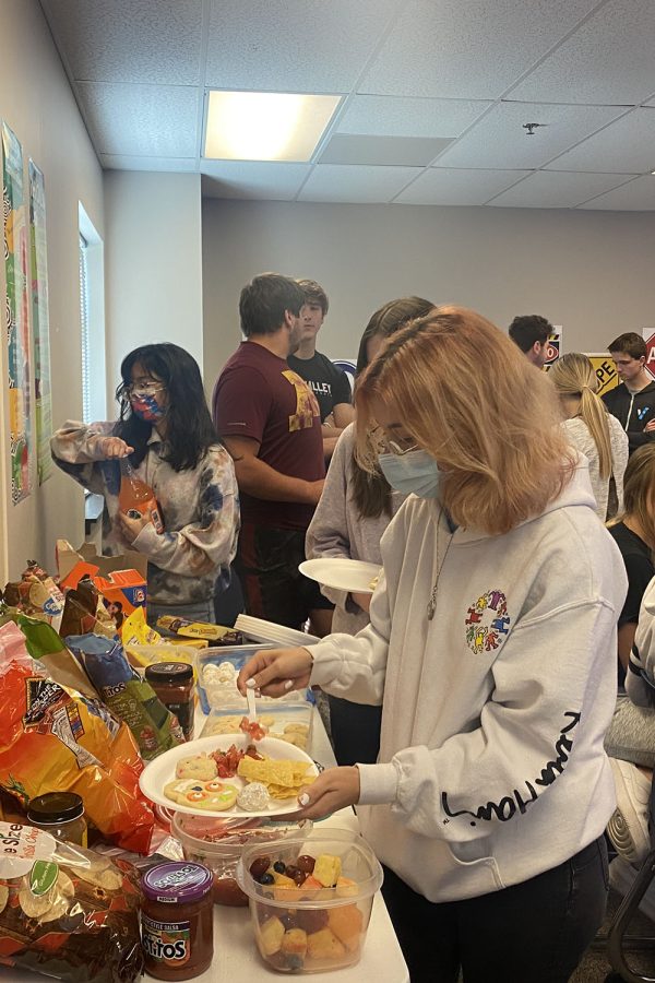 Pouring salsa on to her plate, senior Natalie Hernandez enjoys the party.