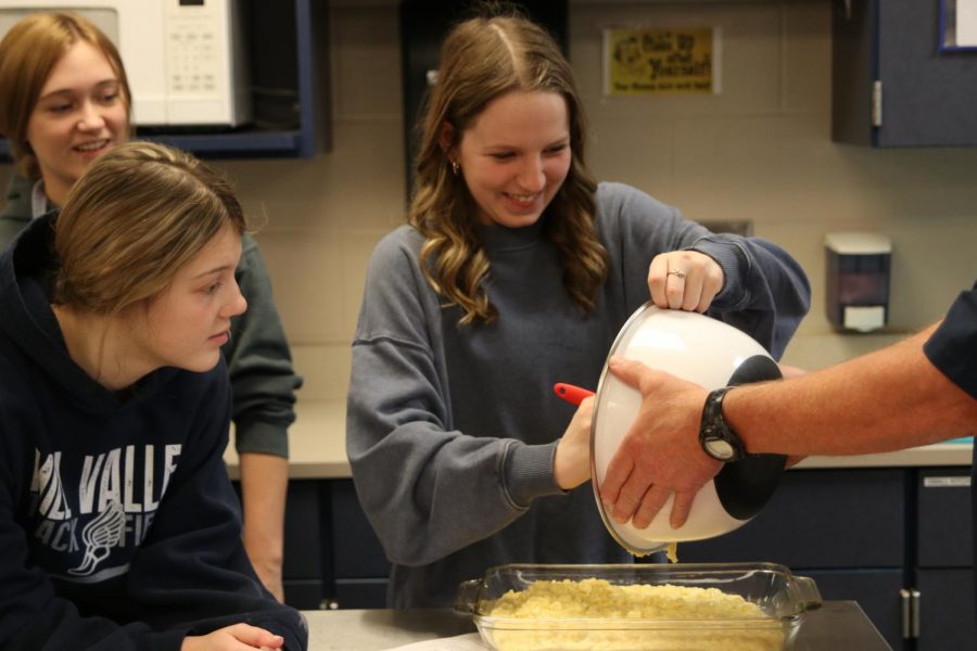 With a smile on her face, junior Paige Dinslage scrapes out the remaining mixture for the hash brown casserole. 