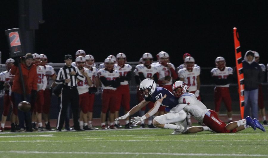 Reaching for the ball, junior Mikey Bergeron attempts the interception while being held back.