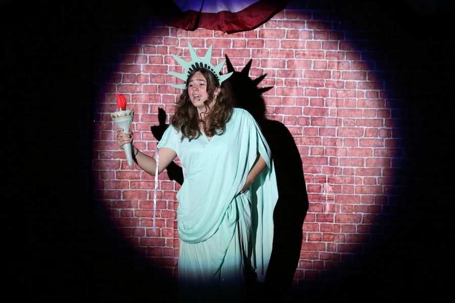 Dressed up as Lady Liberty, Eulalie Shinn played by senior Allison Rader sings under the spotlight. 
