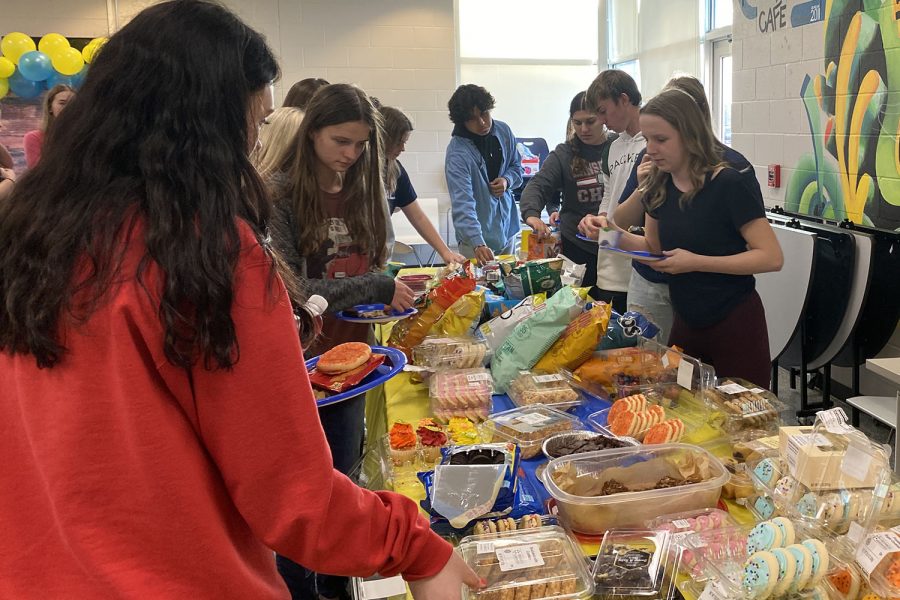 Pouring food on her plate, junior Paige Dinslage goes through the line at the National English Honors Society initiation party.