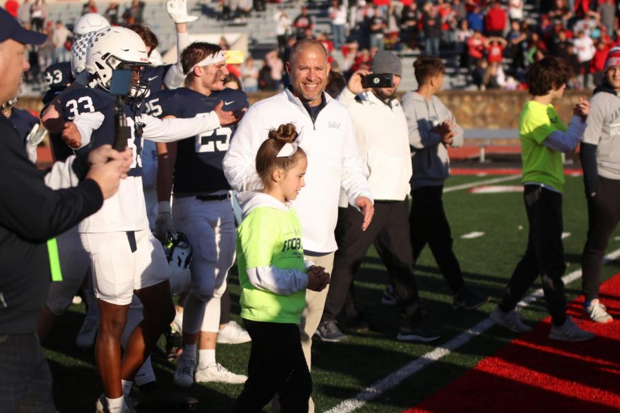 Coach Joel Applebee and his daughter smile as they walk to take the state championship trophy.