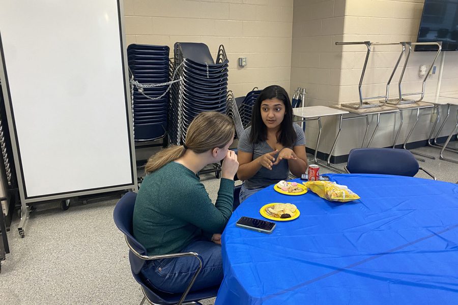 Conversing with one another, sophomore Athena Solomon and junior Cassie Frias talk during the National English Honors Society initiation party 