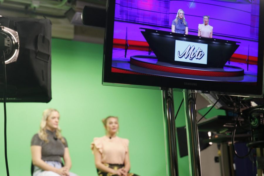 With MVTV show background in view, sophomore Trinity Baker and senior Christine Turner rehearse their lines as anchors for the show in the front of green background Thursday Dec. 2 Photo by Amy Hill 
