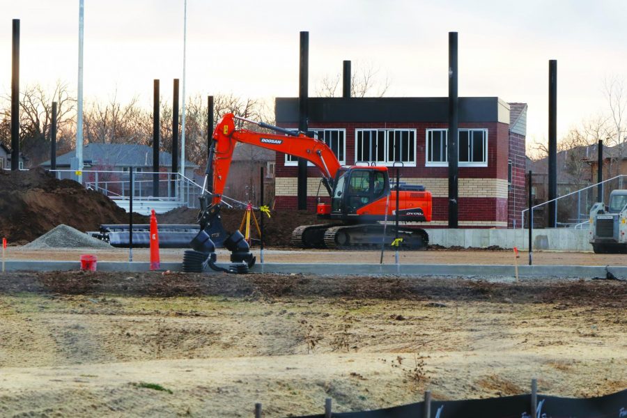 An excavator sits parked in front of the new softball press box and bleachers. The excavator was used to remove dirt in order to level the field so the future turf can be laid down.