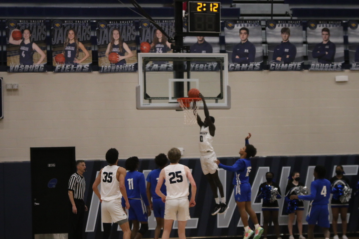Reaching to dunk the basketball, junior Nen Matlock secures the point.