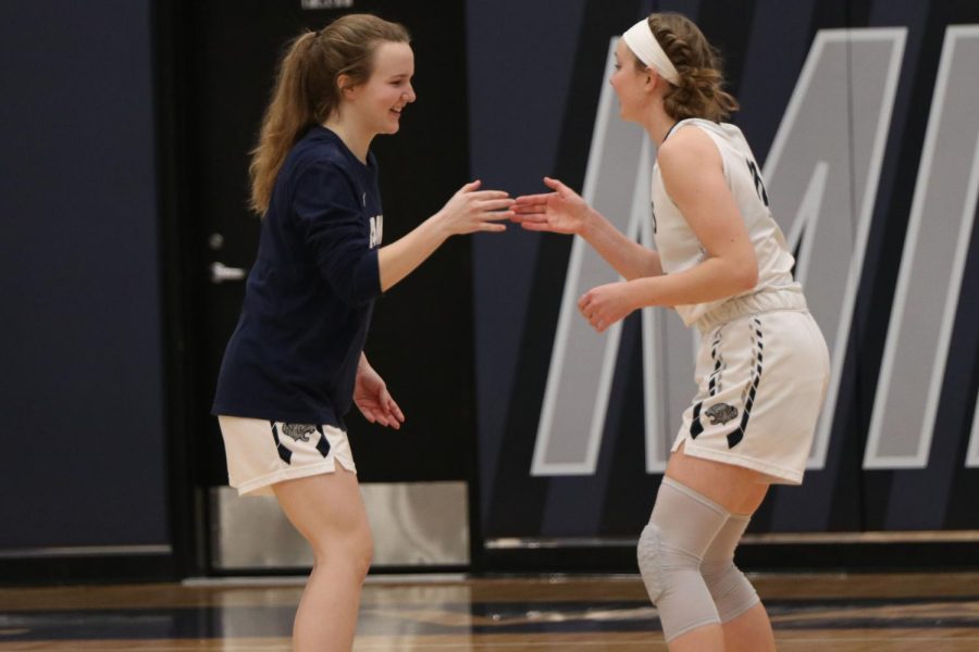 As their names are announced, seniors Greta Trowbridge and Emree Zars high five before the game begins. 