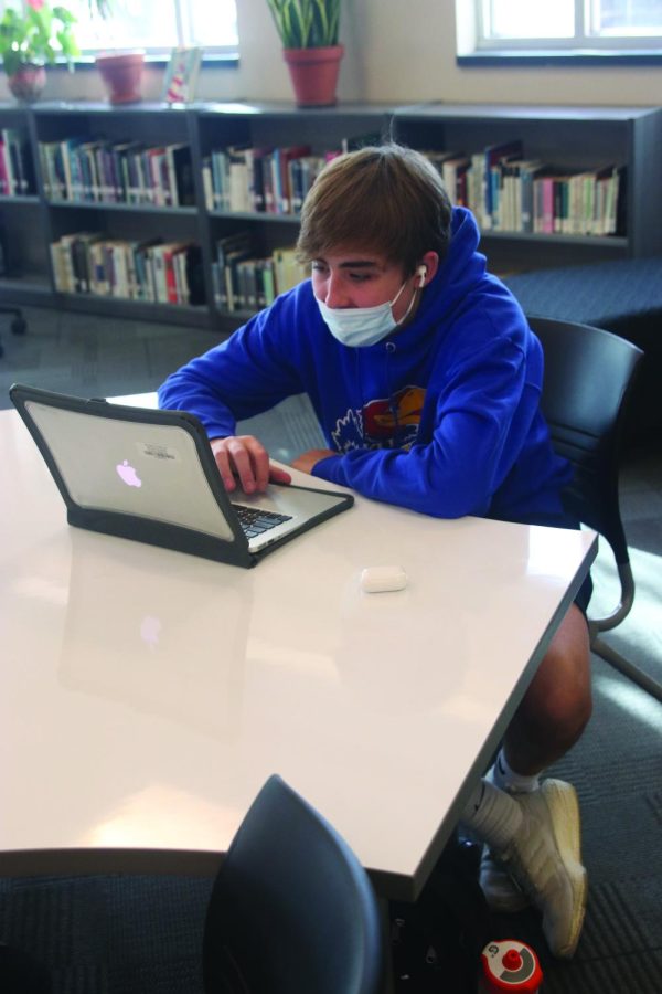 Completing his homework at one of the new library tables Tuesday, Jan 18, sophomore Lincoln Gray works independently. Including window seats, there are 18 new tables in the library.