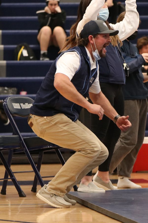 On the edge of the wrestling mat, coach Jake Ellis cheers as freshman Raina Frantz pins her opponent and wins the match.