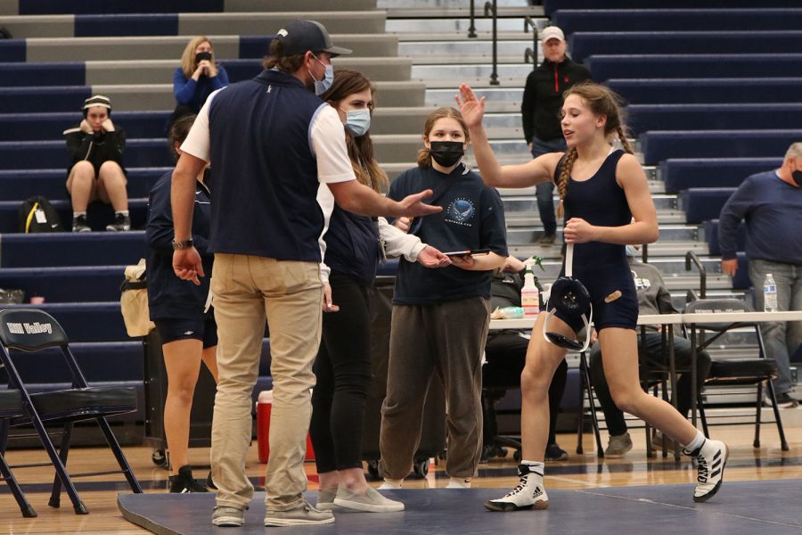Hand in the air, freshman Raina Frantz high fives coaches Jake Ellis and Michelle McRay after winning her match.
