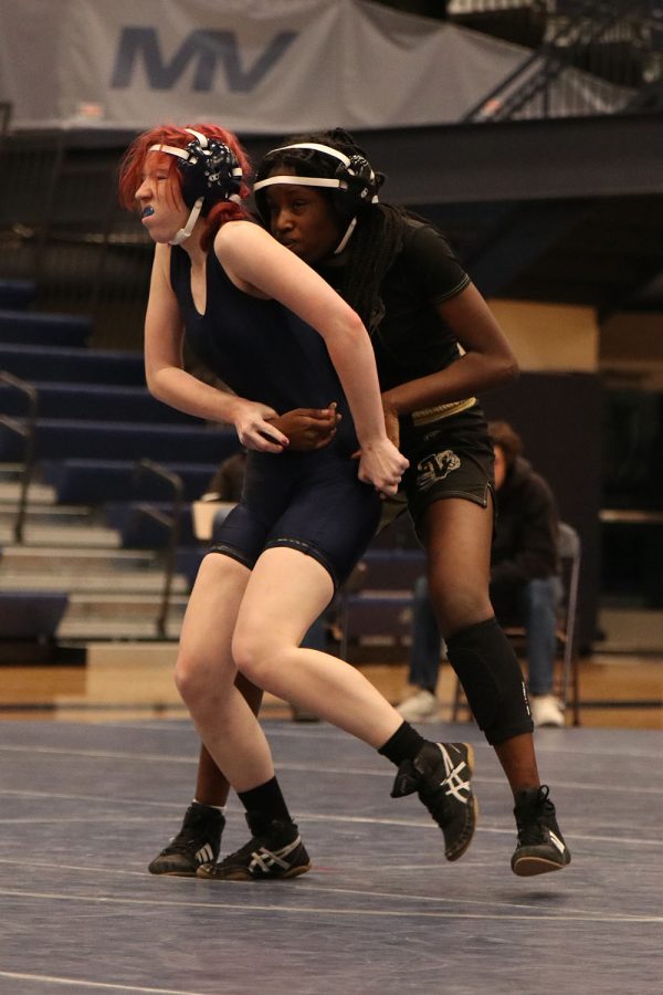 While her opponent’s arms circle her waist, freshman Cadence Kerr tries to escape her grip.
