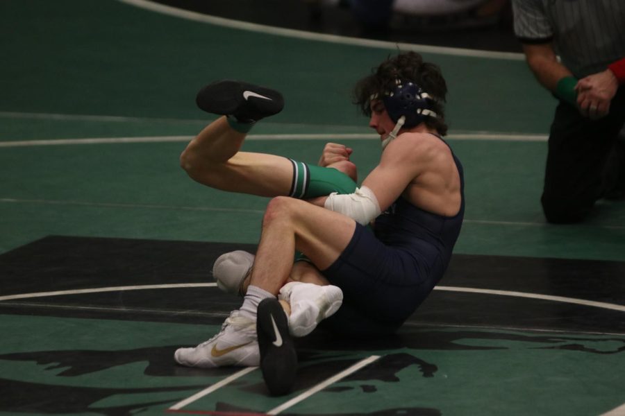 Holding his Derby opponent, sophomore Maddox Casella tries to pin him on the wrestling mat.