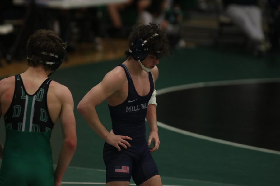 After his first match, sophomore Maddox Casella stands on the wrestling mat to catch his breath.