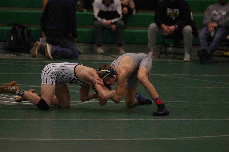 Leaning forward, sophomore Colin McAlister maneuvers his arms to take down his opponent at the Derby Invitational on Saturday, Jan. 8.