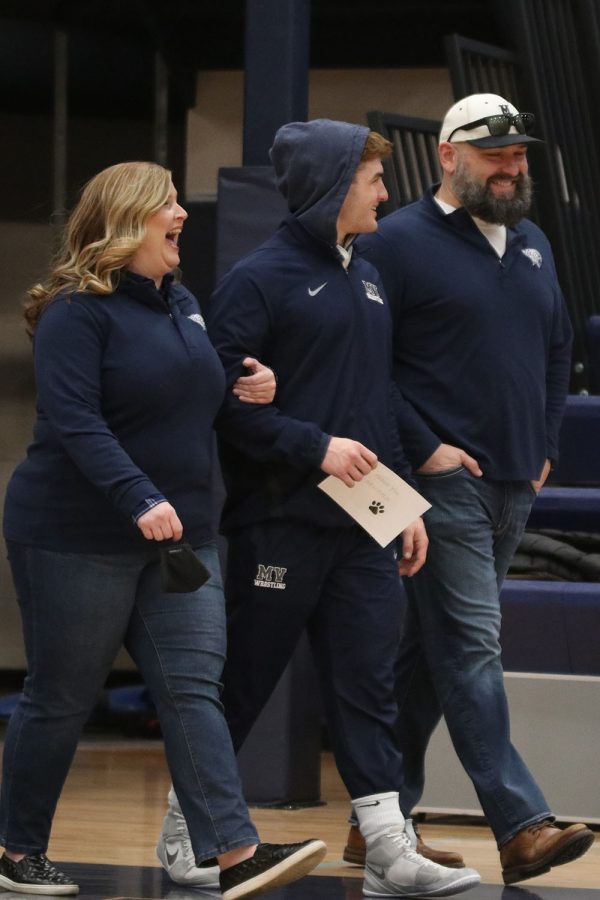 Smiling with his arm intertwined with his mom, senior Payton Douglas walks out with his parents to celebrate his senior wrestling season. 