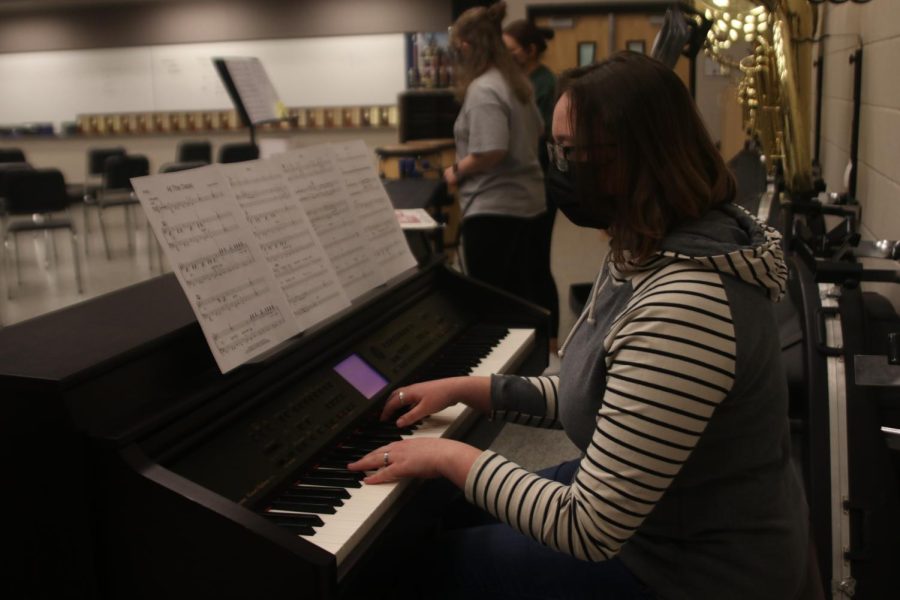 Looking at the music sheet, junior Kate Hereth plays the piano. 