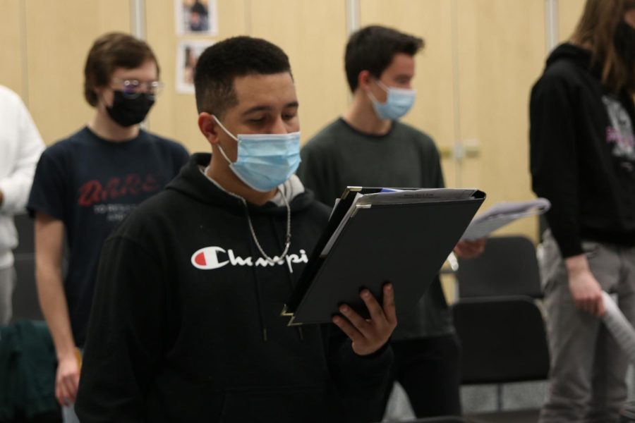 Holding the binder with sheet music, senior Damon Standen-Loyd sings his song during Jag Singers.