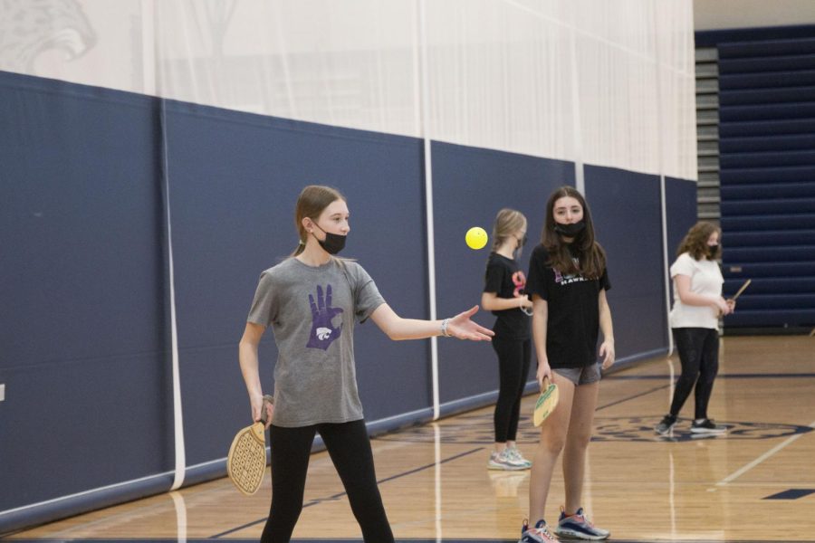 Holding the pickleball paddle, freshman Stella Platt serves the wiffle ball to start the game. 